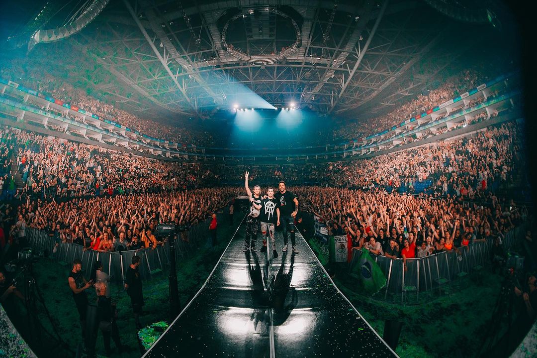 Muse on stage with crowd behind them
